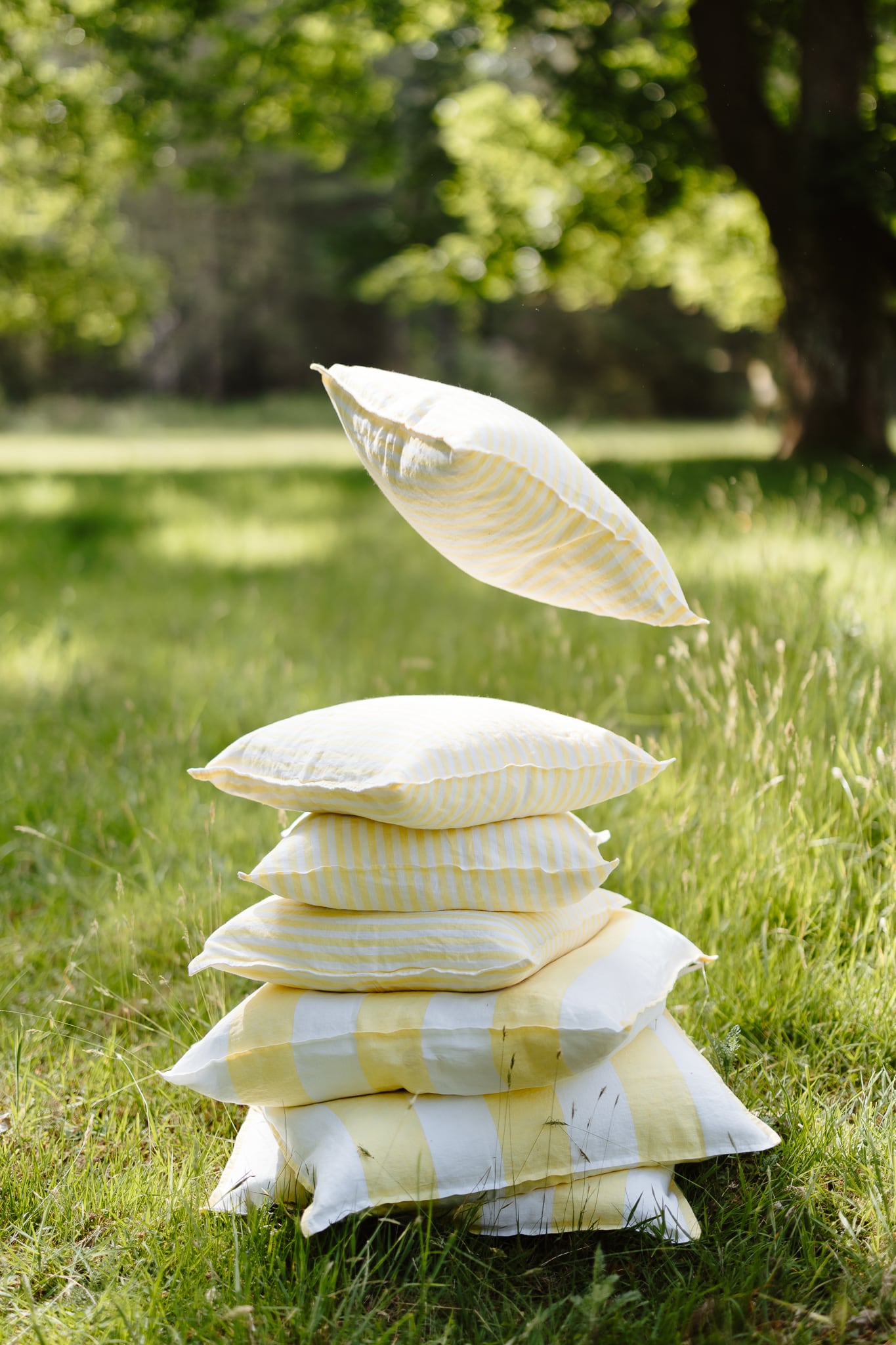 Stack of pillows with a yellow and white pattern on grass