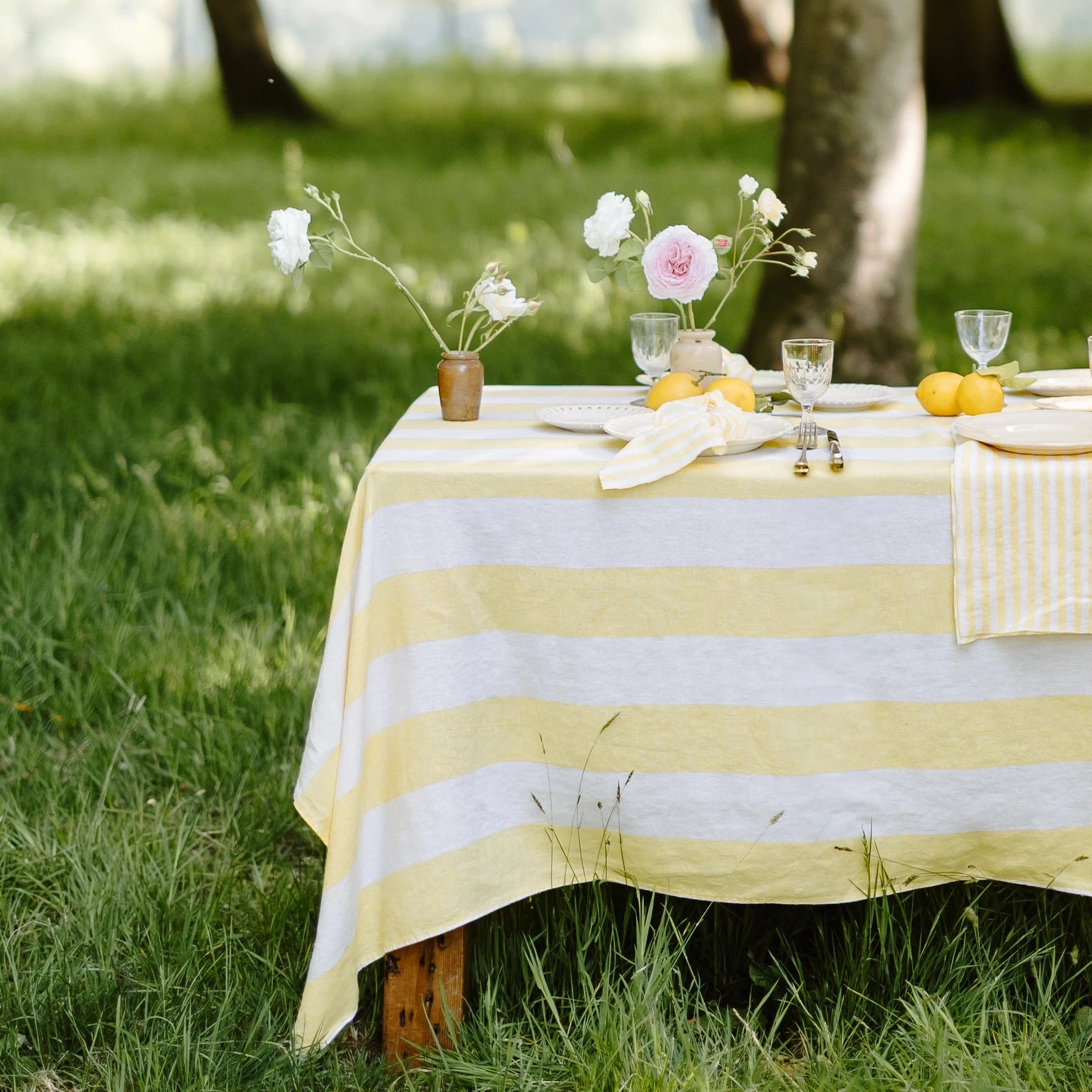 Outdoor table setting with striped tablecloth and flowers in a garden
