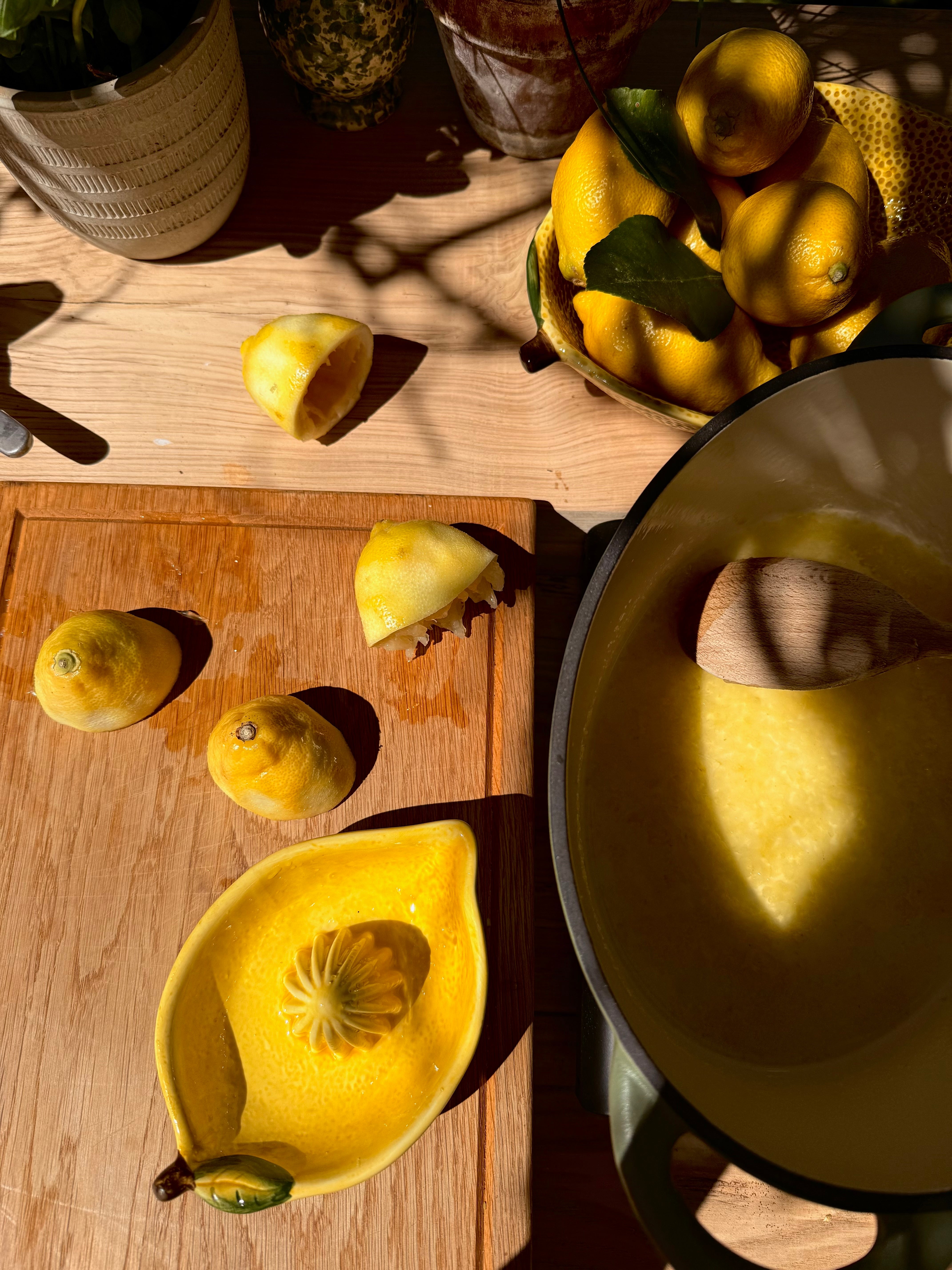 Yellow fruit on a wooden surface with a pot and spoon in the foreground