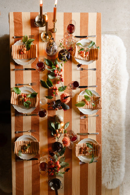 Dining table with a checkered tablecloth set for a meal, featuring plates, cutlery, and centerpieces.