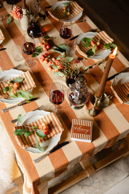 Dining table set with plates, glasses, and a striped tablecloth.