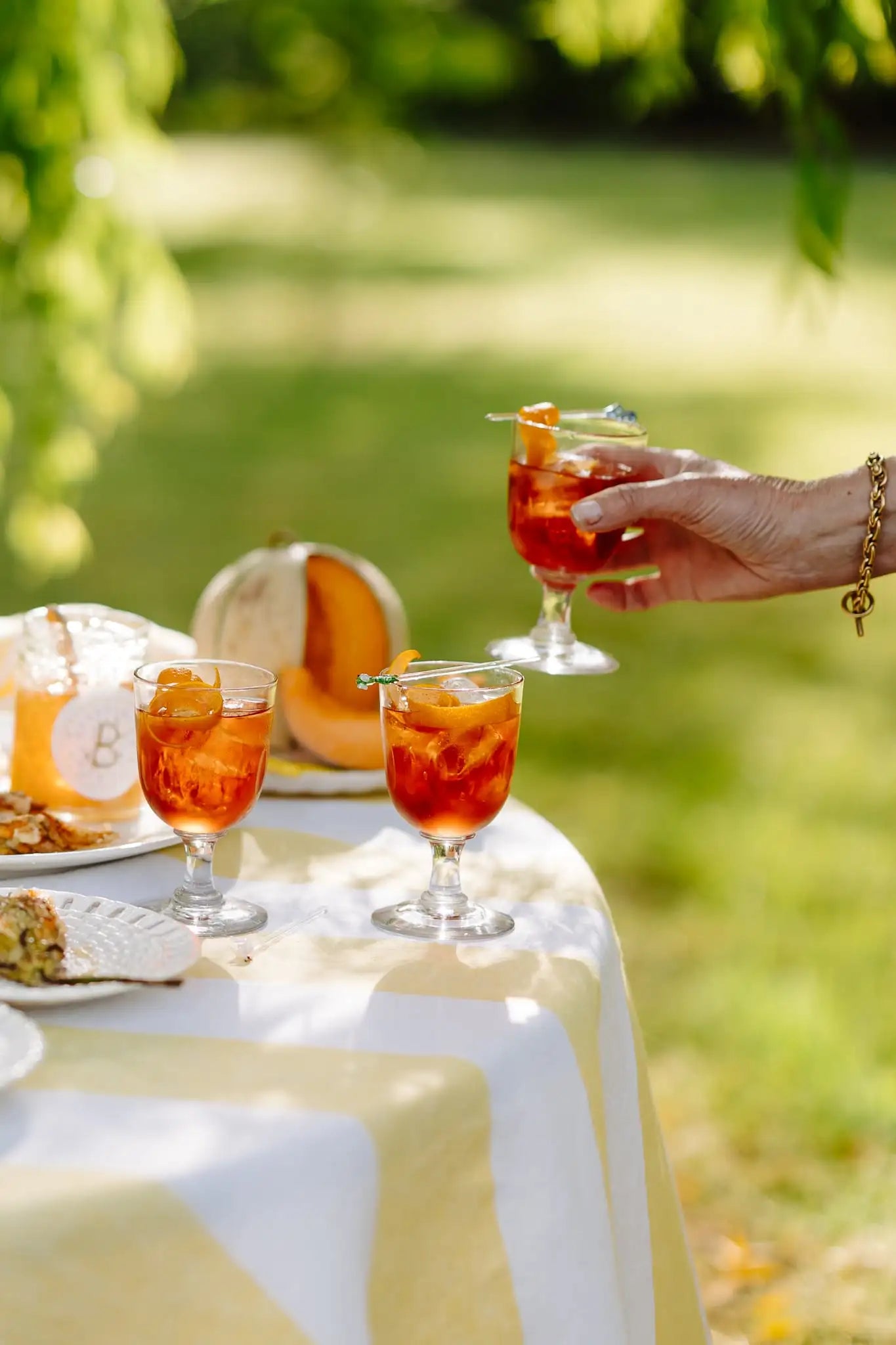 Clodagh McKenna holding a glass of negroni outdoors with a table and greenery in the background