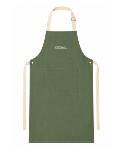 An olive green kitchen apron with cream-colored neck strap, waist ties, and a front pocket, featuring the brand name 'CLODAGH' printed in white near the top center.